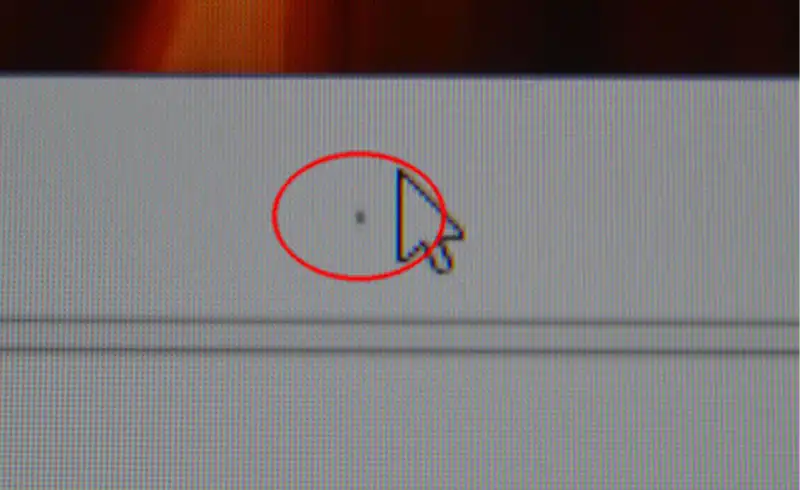 Macro extrem pe un display MacBook cu cursorul macOS vizibil si un pixel negru mort permanent incercuit cu rosu langa cursor — defect tipic de panou OLED/LCD aftermarket de calitate inferioara