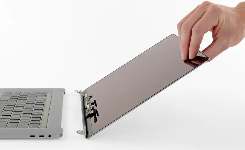 Tehnician demontează panoul displayului de pe topcase-ul unui MacBook Pro pentru înlocuire