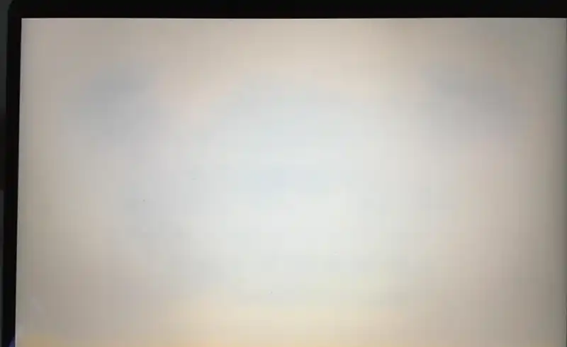 Display MacBook care afiseaza alb pur dar cu un cast galben-bronz evident in zona centrala — semn ca panoul are calibrare slaba sau ca filtrul UV s-a degradat in straturile interne